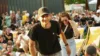 Im Vordergrund ist ein Mitarbeitender zu sehen. Er trägt ein N&M T-Shirt und eine Cap. Im Hintergrund sind viele Menschen auf Liegen zu sehen. Das Bild gibt einem eine Festival-Atmosphäre.