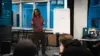 Ein Mitarbeiter hält einen Vortrag. Neben ihm steht ein Whiteboard mit Notizen drauf.